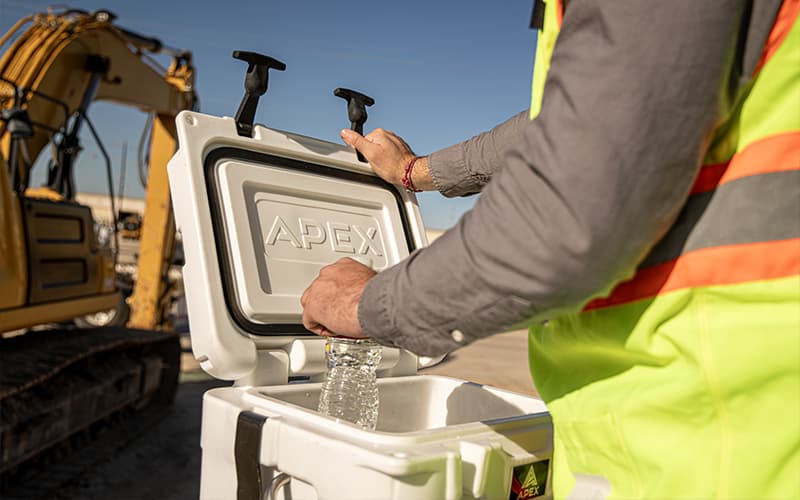 Person grabbing a water bottle on a job site from a White Apex A20 cooler