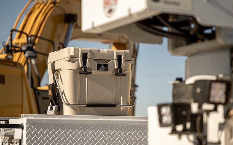 Khaki Apex A20 cooler securely mounted to a work truck sitting at a job site