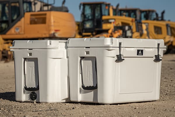 Two Apex coolers in front of construction equipment on a job site