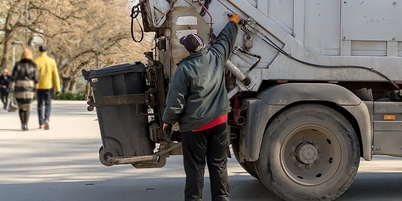 Municipal worker operating a garbage truck on a city street